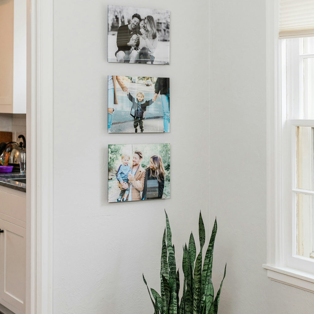 Three acrylic prints hanging in a column by a window