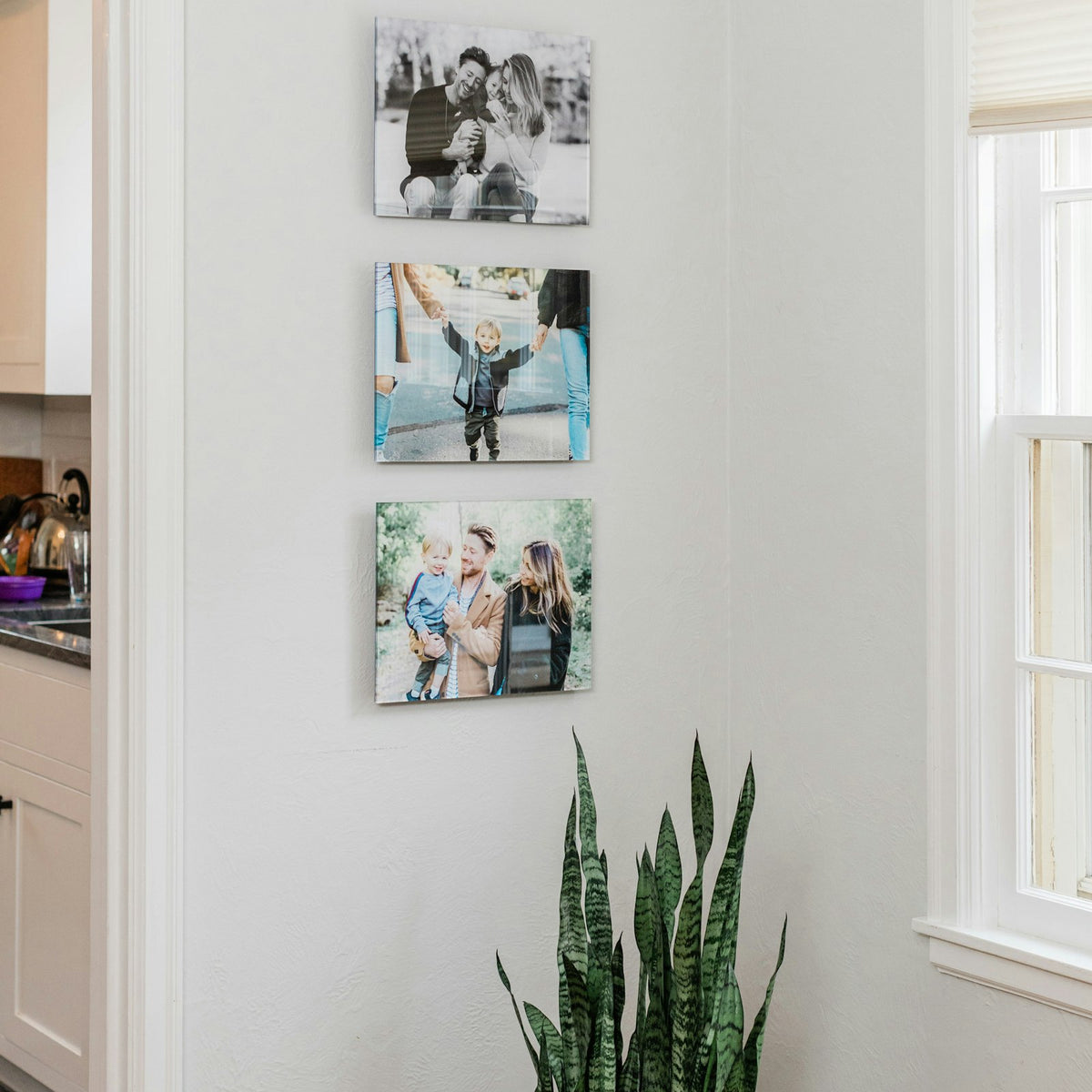 Three acrylic prints hanging in a column by a window